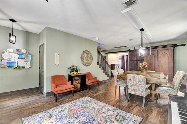 This inviting dining area is shared with a family room, all set on warm wood-look flooring. Large windows provide ample natural light The staircase leads to the upper level | Image 5