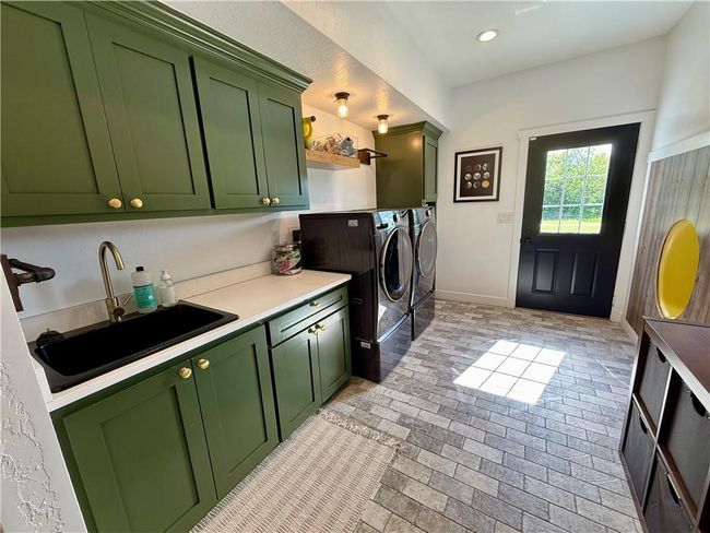Washroom featuring organized storage with custom cabinetry, washer and clothes dryer, brick patterned flooring. | Image 22