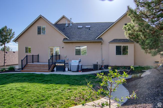 Rear view of property with roof with shingles, central air condition unit, a wooden deck, a yard, and stucco siding | Image 44