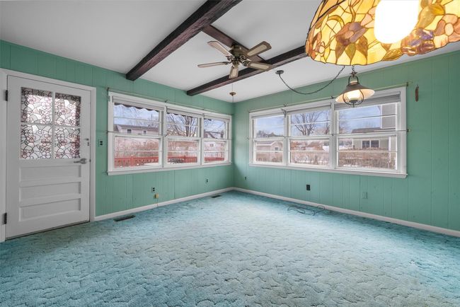 Unfurnished sunroom with a ceiling fan, visible vents, and beamed ceiling | Image 17