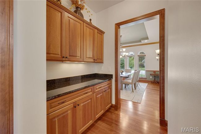 Kitchen featuring a chandelier, light wood-style flooring, and dark stone countertops | Image 20