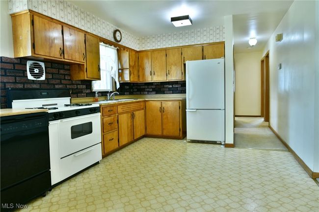 Kitchen with a sink, brown cabinets, white appliances, light floors, and light countertops | Image 16