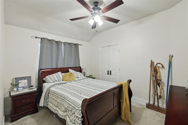 Carpeted bedroom featuring a closet, vaulted ceiling, and a ceiling fan | Image 31