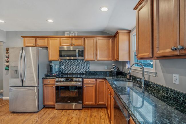 Kitchen featuring sink, backsplash, stainless steel appliances, light hardwood / wood-style floors, and dark stone counters | Image 9