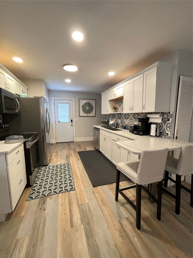 Kitchen with white cabinetry, range, backsplash, recessed lighting, and light wood finished floors | Image 4