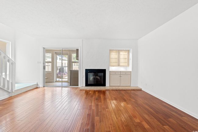 Unfurnished living room featuring hardwood / wood-style floors, a glass covered fireplace, and a textured ceiling | Image 4