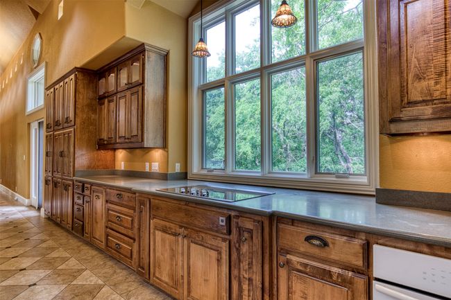 Kitchen with an abundance of cabinetry and serene views of back of estate and courtyard. | Image 14