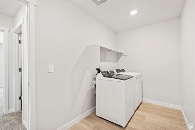 Washroom featuring washer and clothes dryer, baseboards, and light wood-type flooring | Image 22