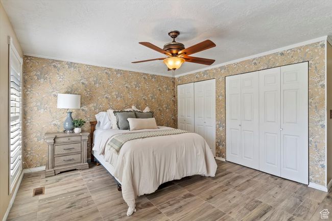 Bedroom with wallpapered walls, ornamental molding, multiple closets, a textured ceiling, and baseboards | Image 17