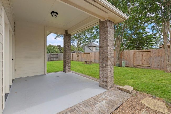 Enjoy outdoor living under the covered patio, complete with brick columns and a spacious, fully fenced backyard with mature trees—perfect for relaxing or entertaining. | Image 21