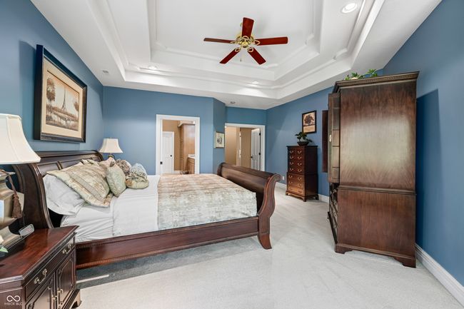 bedroom with connected bathroom, light colored carpet, a tray ceiling, baseboards, and recessed lighting | Image 49