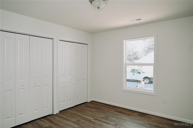 Unfurnished bedroom with dark wood-type flooring and multiple closets | Image 9