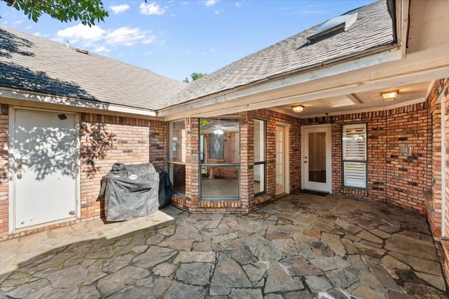 Enjoy a relaxing beverage on this covered, flagstone patio. The patio has access from the primary bedroom, living room and the breakfast room! There is a door to the oversized garage for added convenience. | Image 37
