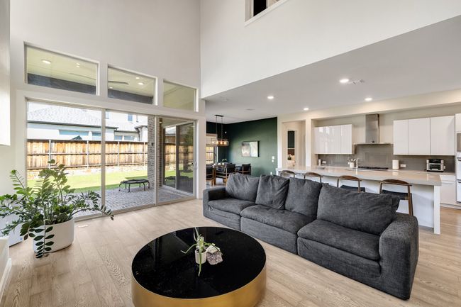 Living room featuring light wood finished floors, a high ceiling, and recessed lighting | Image 16