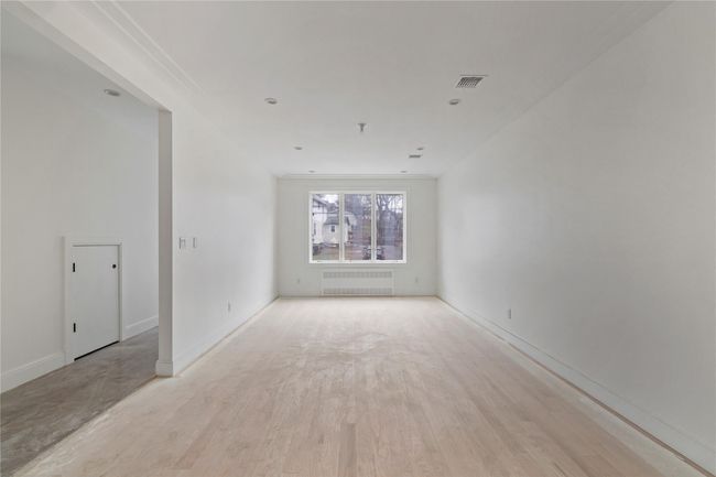 Unfurnished room with radiator heating unit, baseboards, visible vents, and light wood finished floors | Image 11