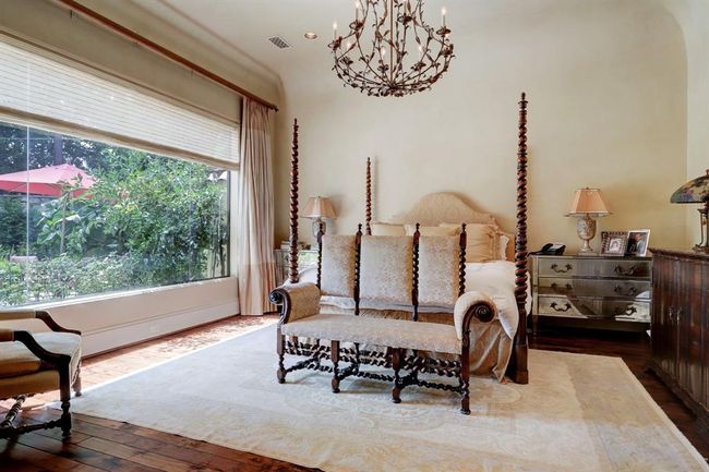 Primary bedroom is located on the first floor overlooking the pool and has sitting area, remote blinds and custom drapes, two chandeliers, French doors to the pool, utility room, custom cabinetry and Segreto finishes in both closets. | Image 19