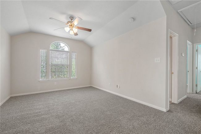 Carpeted spare room with attic access, ceiling fan, vaulted ceiling, and a smoke detector | Image 16