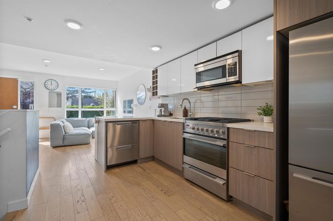Kitchen featuring white cabinets, modern cabinets, open floor plan, light countertops, and stainless steel appliances | Image 13