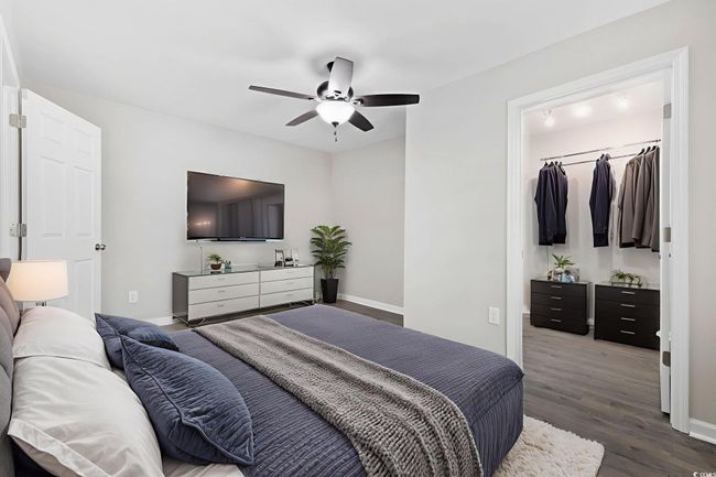 Bedroom with a walk in closet, dark wood finished floors, baseboards, and a closet | Image 25