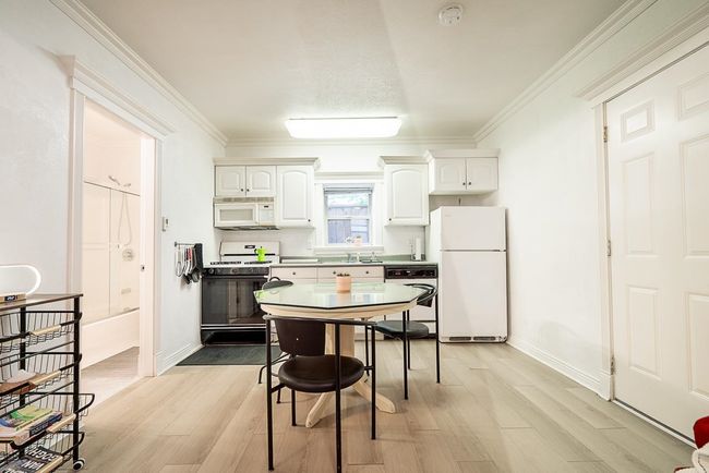Kitchen with white appliances, white cabinets, light wood-style flooring, and crown molding | Image 24