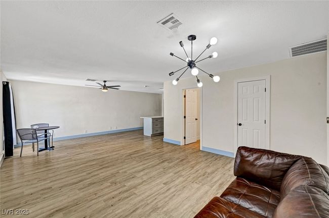Living area with light wood-style flooring, a chandelier, and ceiling fan | Image 9