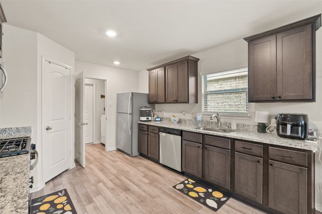 Kitchen with granite counters, dark brown cabinetry, a sink, luxury vinyl floors, and stainless steel appliances | Image 10