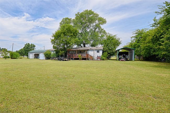 View of green lawn featuring a carport, a deck, and an outbuilding | Image 30