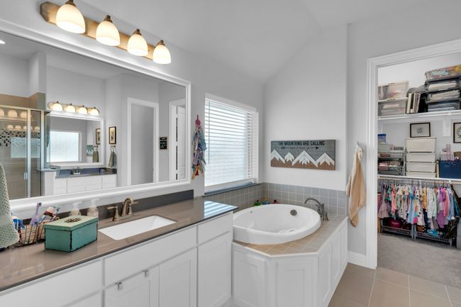 Bathroom featuring vanity, a walk in closet, a garden tub, tile patterned floors, and vaulted ceiling | Image 20