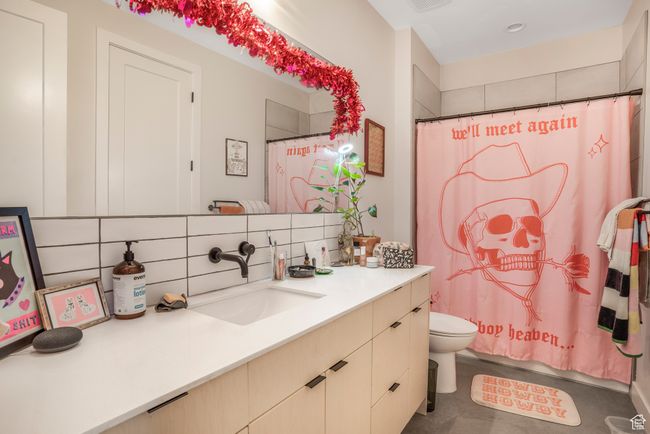 Bathroom featuring toilet, decorative backsplash, a shower with shower curtain, and vanity | Image 42