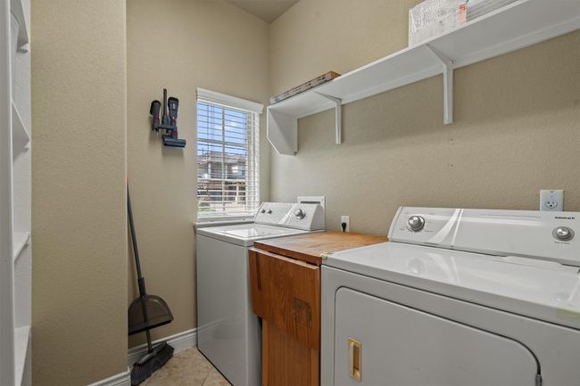 Washroom with washing machine and clothes dryer, light tile patterned floors, and baseboards | Image 16