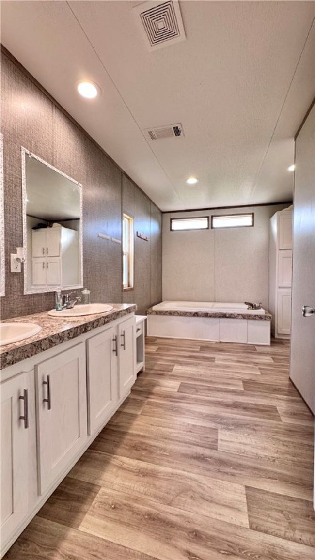 Full bathroom featuring a textured ceiling, double vanity, wood finished floors, a garden tub, and recessed lighting | Image 19