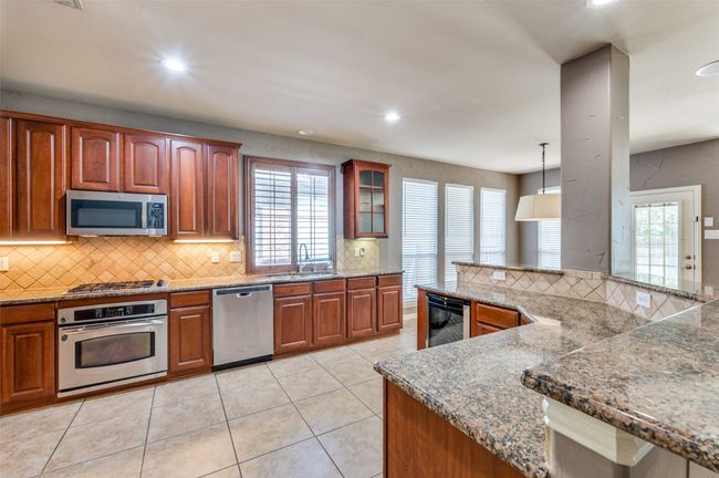 Kitchen with stainless steel appliances, tasteful backsplash, recessed lighting, granite countertops, and great room flow | Image 8