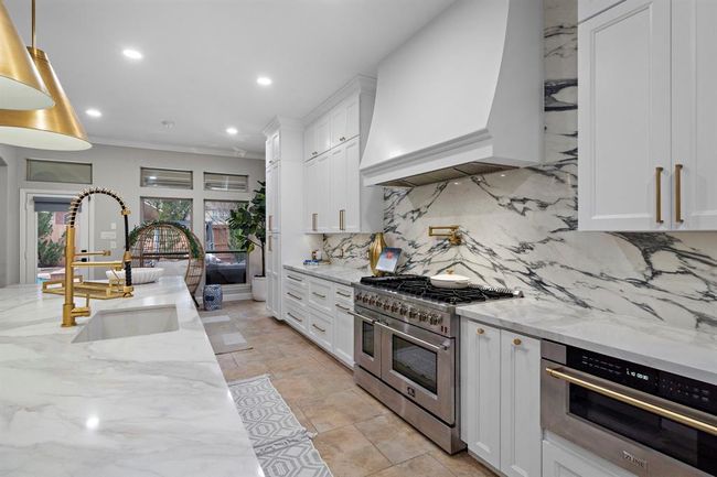 A true highlight of the space is the porcelain backsplash, paired with high-end Buster + Punch outlets for a touch of sophistication. The oversized 24-inch drum lighting adds an elegant pop, enhancing the kitchen’s luxurious feel. | Image 14