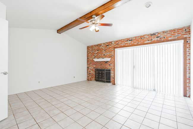 Unfurnished living room featuring light tile patterned flooring, a fireplace, lofted ceiling with beams, and a ceiling fan | Image 29