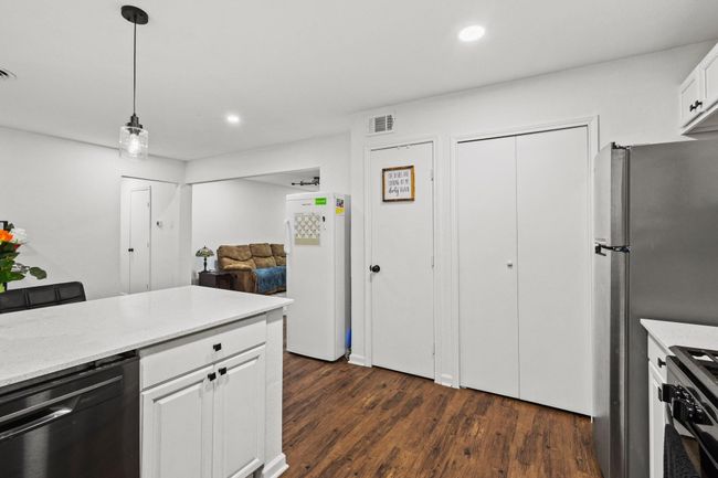 Kitchen with freestanding refrigerator, dishwasher, gas range, white cabinets, and dark wood finished floors | Image 33