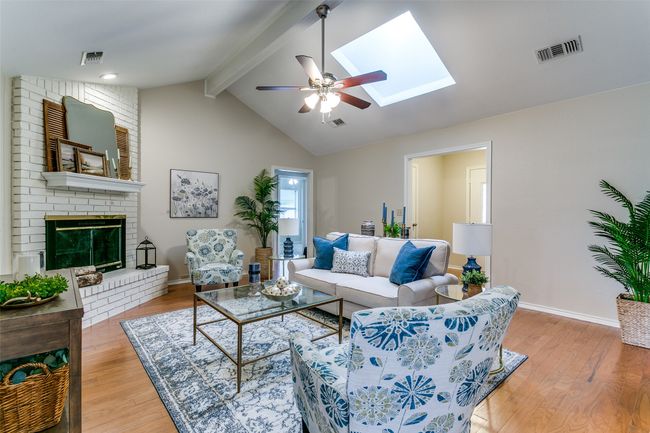 Living area with ceiling fan, light wood-style floors, a skylight, and a brick fireplace | Image 8