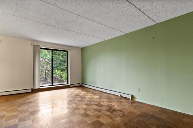 room with a baseboard heating unit, a textured ceiling, and a baseboard radiator | Image 6