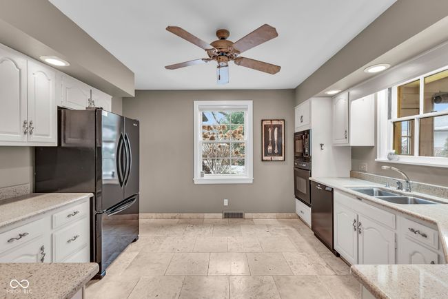 kitchen featuring white cabinetry, visible vents, black appliances, and a sink | Image 11