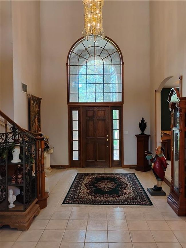 Tiled entrance foyer featuring an inviting chandelier, a towering ceiling, arched walkways, and plenty of natural light | Image 13