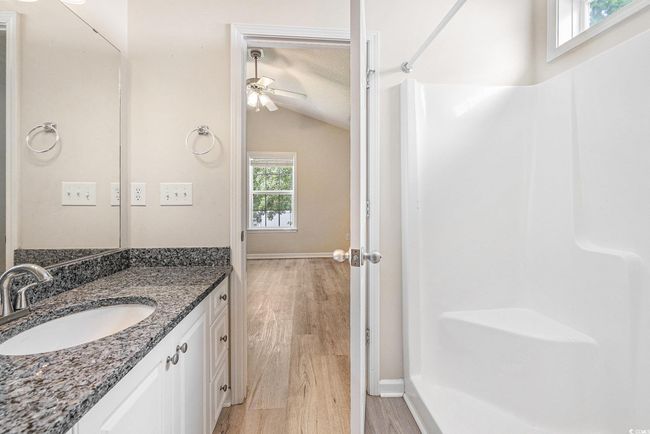 Full bathroom featuring vaulted ceiling, vanity, a shower, wood finished floors, and a ceiling fan | Image 24
