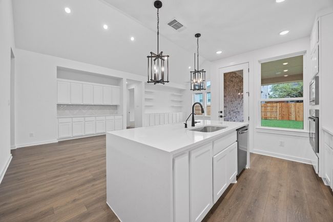 Kitchen with appliances with stainless steel finishes, a kitchen island with sink, a chandelier, white cabinetry, and recessed lighting | Image 5