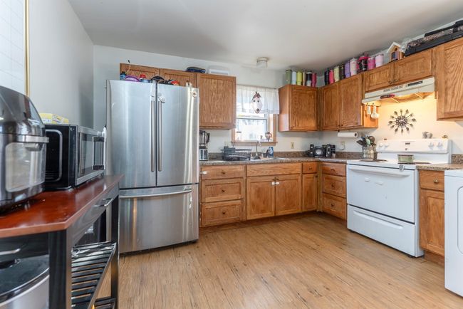 Kitchen featuring a sink, brown cabinetry, appliances with stainless steel finishes, and under cabinet range hood | Image 29