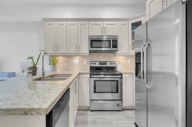 Kitchen featuring decorative backsplash, a peninsula, appliances with stainless steel finishes, and a sink | Image 7