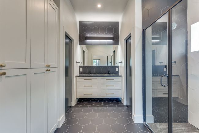 Bathroom featuring vanity, a shower stall, backsplash, and tile patterned floors | Image 12