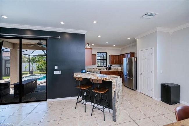 Kitchen featuring freestanding refrigerator, a peninsula, crown molding, and a wealth of natural light | Image 13