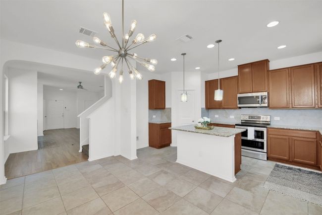 Kitchen featuring appliances with stainless steel finishes, brown cabinets, visible vents, and tasteful backsplash | Image 12