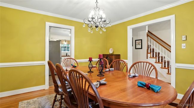 Dining area with a chandelier, crown molding, wood finished floors, and stairs | Image 45