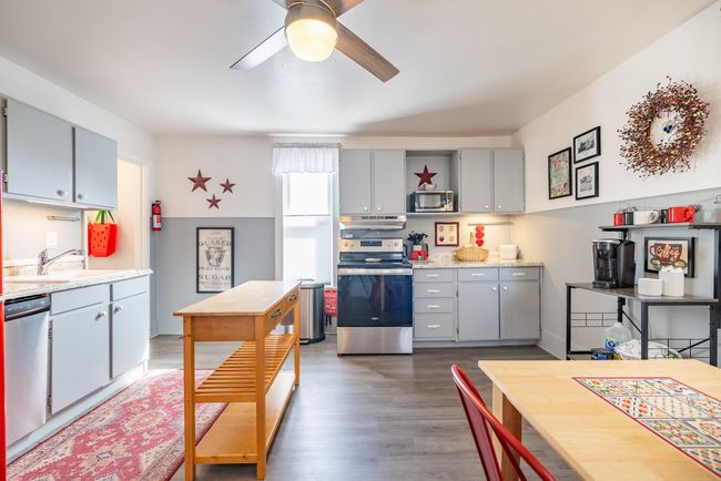 Kitchen with stainless steel appliances, under cabinet range hood, a sink, a ceiling fan, and wood finished floors | Image 23