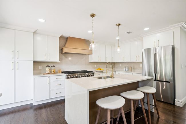 Kitchen with freestanding refrigerator, premium range hood, dark wood-type flooring, light countertops, and tasteful backsplash | Image 5