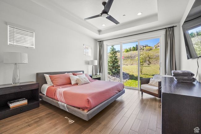 Bedroom featuring a tray ceiling, wood finished floors, access to outside, recessed lighting, and a ceiling fan | Image 16